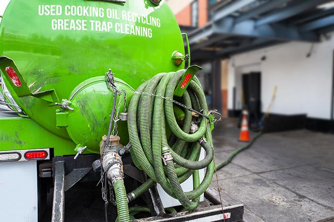 a professional plumber using a pump to empty a grease trap in Granville, OH